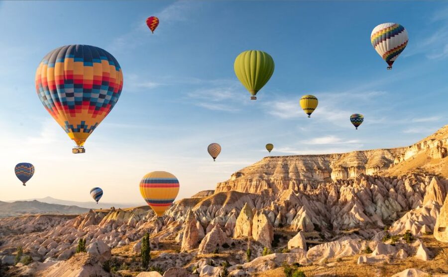 Balloons rising over the tuff cliffs at Göreme before sunrise